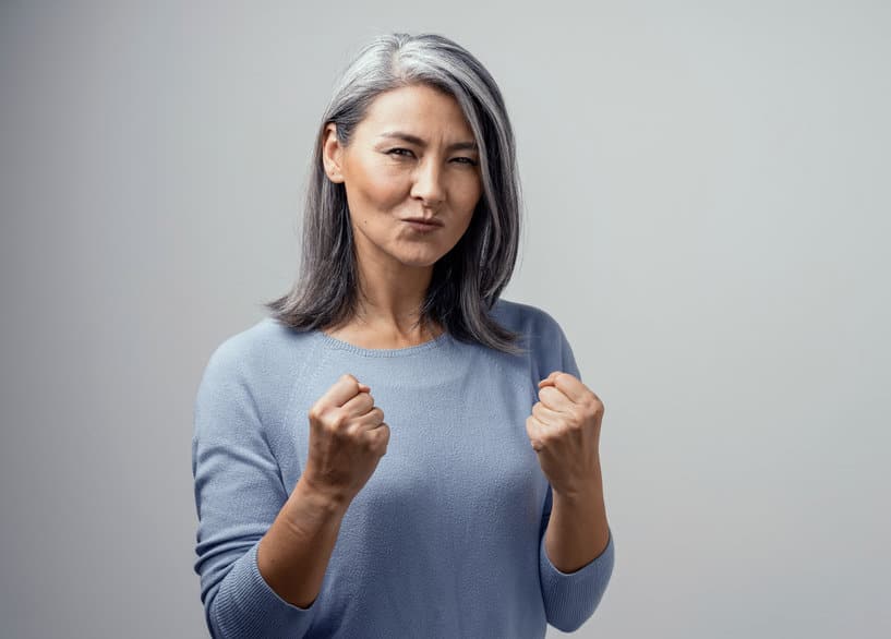 Happy Mature Asian Female Model Smiles Happily. She Celebrates Victory and Holds Fists in Satisfaction. Hand Photo in Studio on White Background
